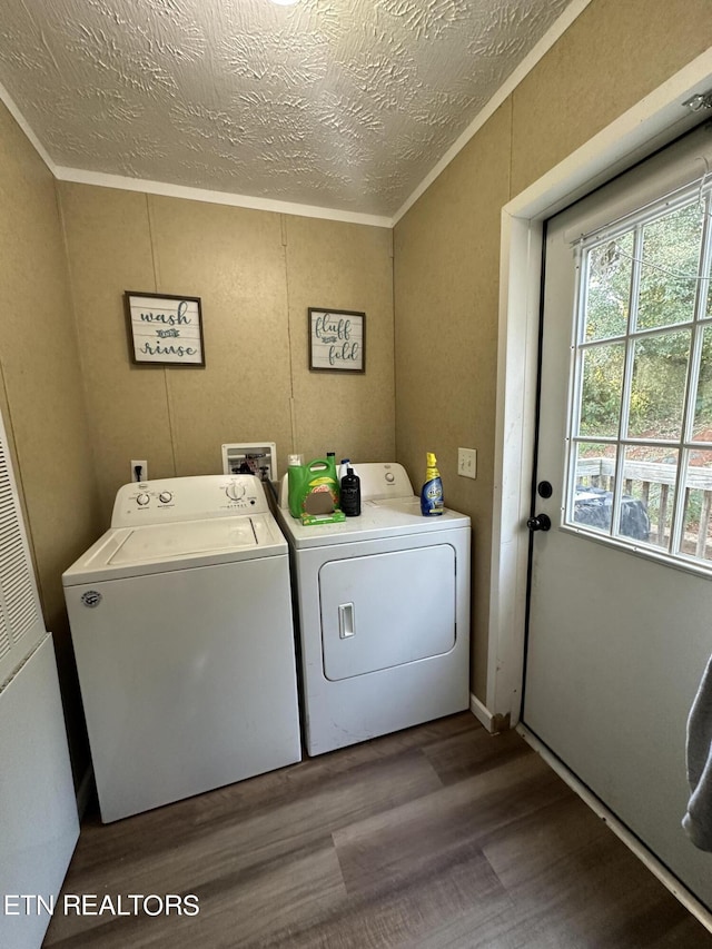 clothes washing area with laundry area, washing machine and dryer, a textured ceiling, and wood finished floors