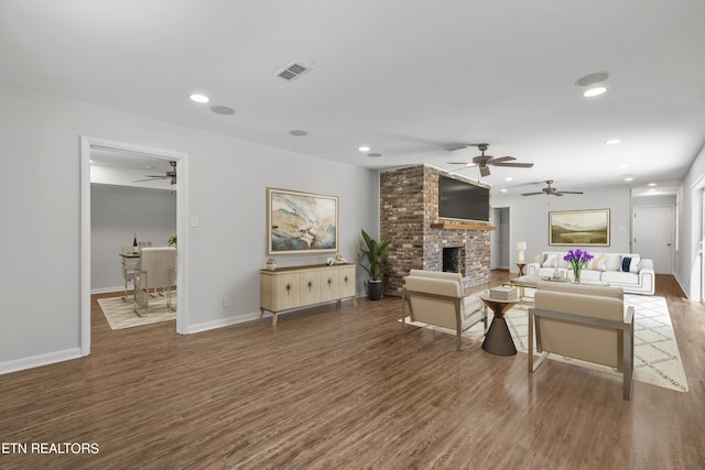 living room featuring a fireplace, ceiling fan, and dark hardwood / wood-style floors