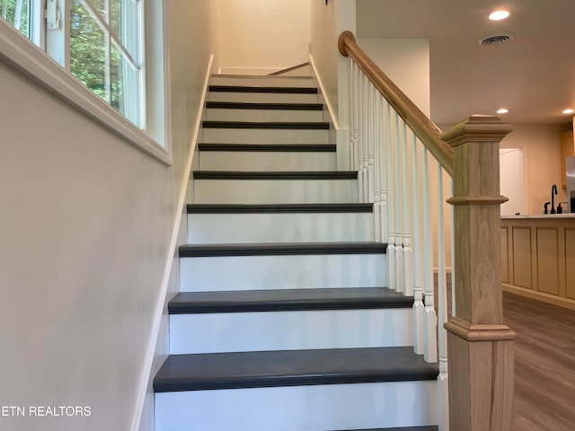 staircase with wood-type flooring and sink