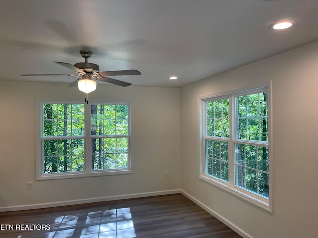 empty room featuring ceiling fan, plenty of natural light, and dark wood-type flooring