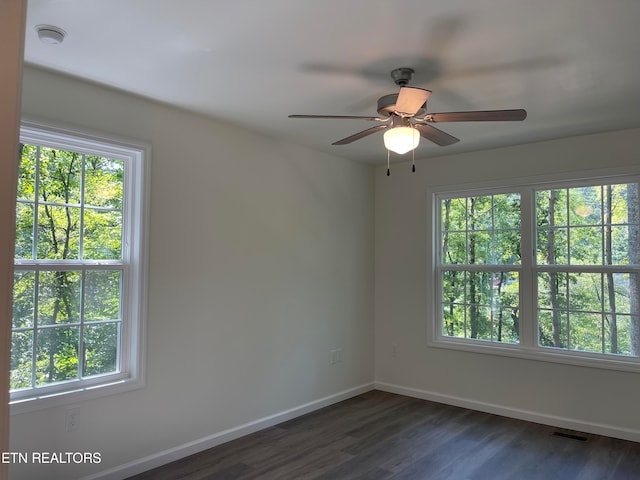 empty room with dark hardwood / wood-style flooring, plenty of natural light, and ceiling fan