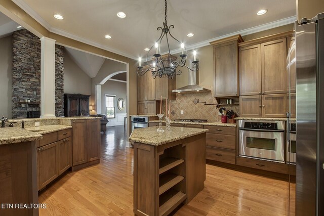 kitchen featuring light wood-type flooring, ornamental molding, stainless steel appliances, a center island, and lofted ceiling