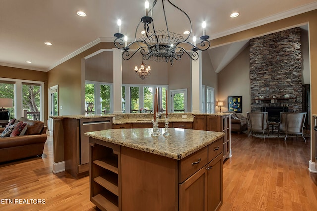 kitchen featuring a fireplace, a notable chandelier, light hardwood / wood-style floors, a center island, and a healthy amount of sunlight