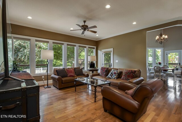 living room with ceiling fan with notable chandelier, crown molding, and hardwood / wood-style floors