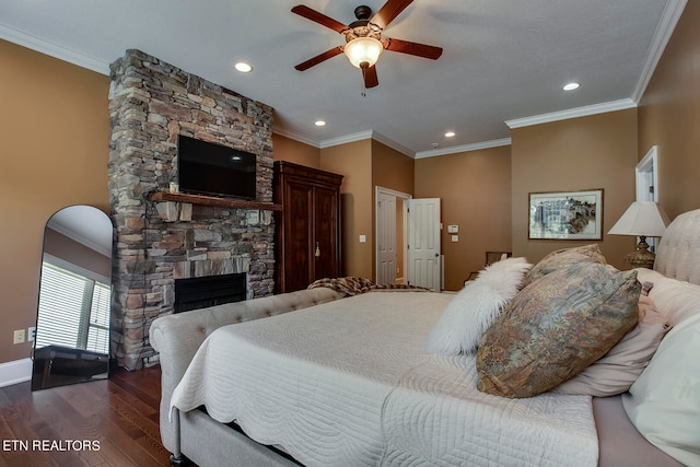 bedroom featuring crown molding, a stone fireplace, ceiling fan, and dark hardwood / wood-style floors