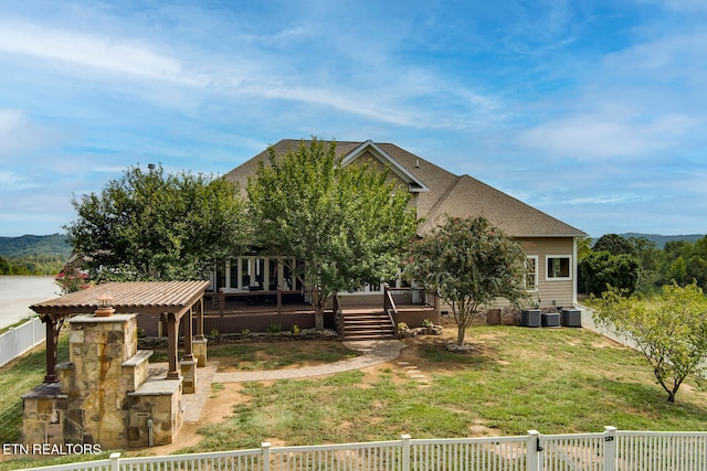 view of front facade with a front lawn, a wooden deck, and cooling unit