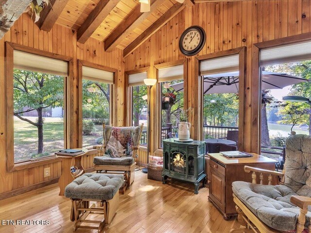 sunroom / solarium featuring wood ceiling, a wood stove, and vaulted ceiling with beams