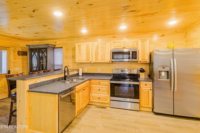 kitchen featuring a breakfast bar, stainless steel appliances, sink, and kitchen peninsula