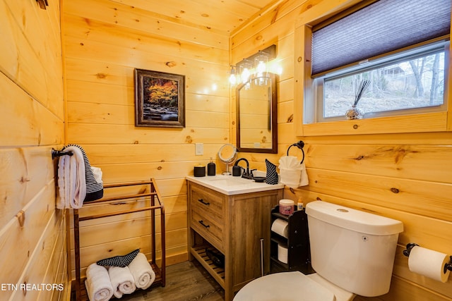 bathroom featuring wood-type flooring, toilet, wooden walls, and vanity