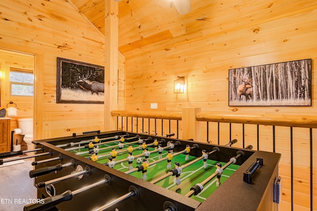 playroom featuring vaulted ceiling, wood walls, and ceiling fan