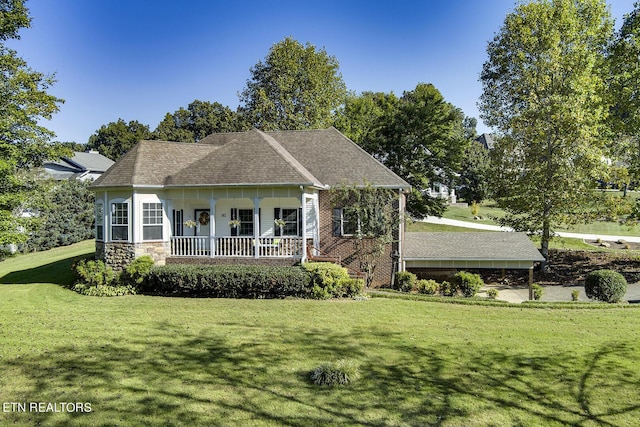 view of front of home featuring stone siding, a front yard, covered porch, and a shingled roof