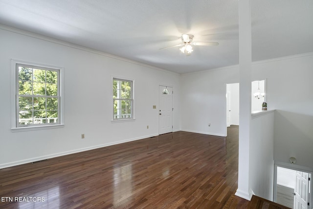 empty room featuring visible vents, baseboards, a ceiling fan, dark wood-type flooring, and crown molding