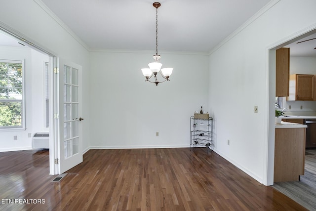 unfurnished dining area with baseboards, a wall unit AC, dark wood-type flooring, an inviting chandelier, and crown molding