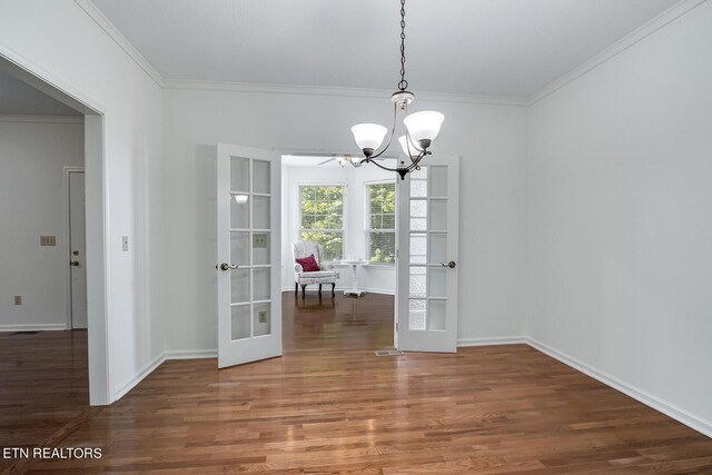 unfurnished dining area with ornamental molding, a chandelier, wood finished floors, and french doors