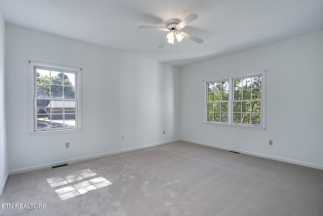 unfurnished room with a wealth of natural light, visible vents, and light carpet