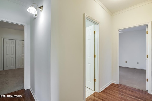 hall with crown molding, baseboards, and wood finished floors