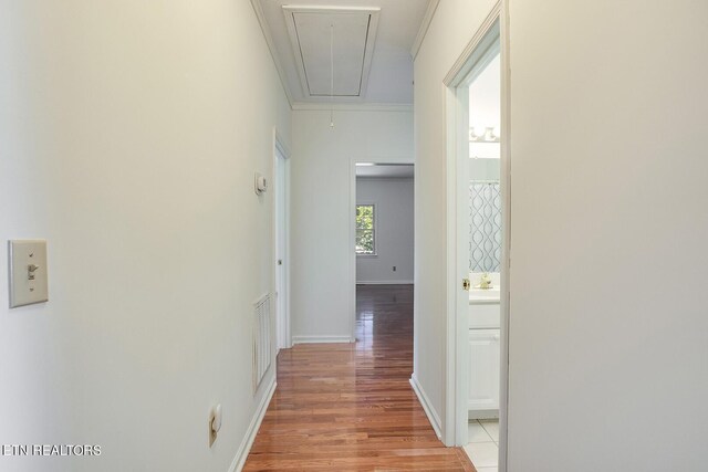 hallway with ornamental molding and light hardwood / wood-style flooring