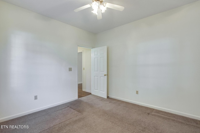 empty room with carpet flooring, a ceiling fan, and baseboards