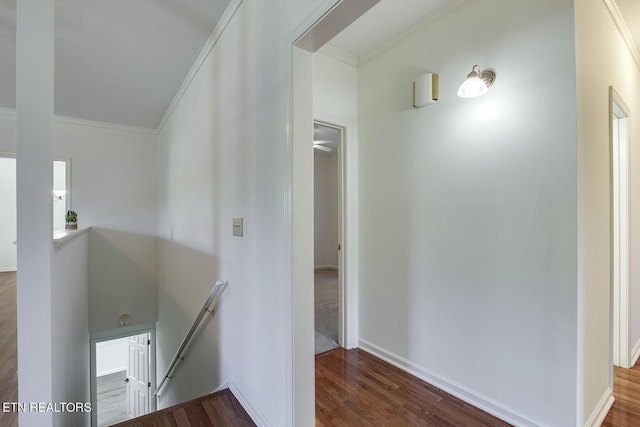 hallway featuring baseboards, wood finished floors, an upstairs landing, and crown molding