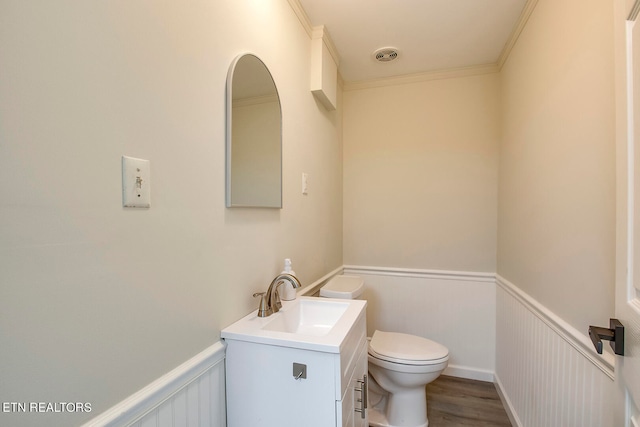 bathroom with vanity, toilet, ornamental molding, and hardwood / wood-style floors