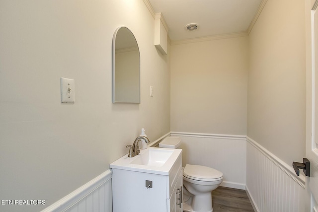 half bathroom with visible vents, wainscoting, toilet, wood finished floors, and vanity