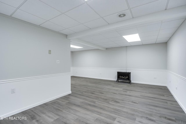 spare room with a drop ceiling, wood finished floors, visible vents, wainscoting, and a wood stove