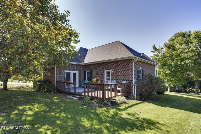 back of house with a yard, brick siding, roof with shingles, and a wooden deck