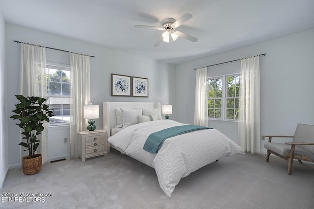 bedroom featuring multiple windows, a ceiling fan, and light colored carpet