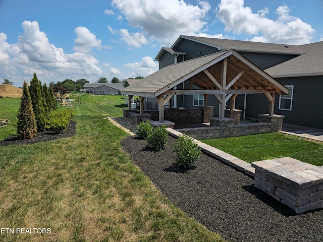 rear view of house featuring a shingled roof, stone siding, a patio area, and a yard