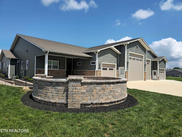 view of front of house with a front yard, stone siding, an attached garage, and concrete driveway