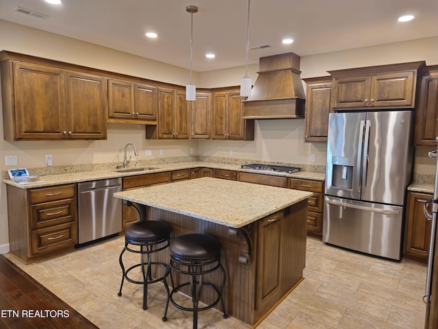 kitchen with pendant lighting, premium range hood, a center island, stainless steel appliances, and sink