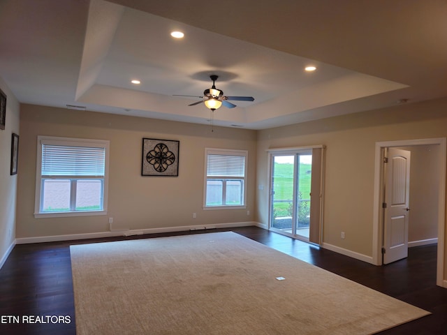 unfurnished room featuring a tray ceiling, dark wood-type flooring, and recessed lighting