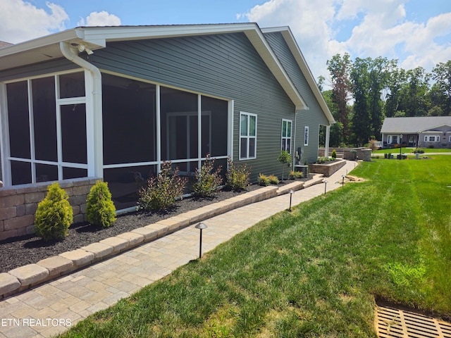 view of side of property with a sunroom and a yard