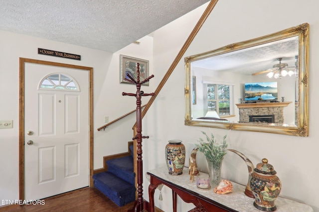 entryway featuring hardwood / wood-style flooring, plenty of natural light, a textured ceiling, and a stone fireplace