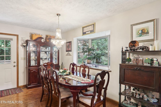 dining room featuring dark wood-type flooring, an inviting chandelier, and a textured ceiling