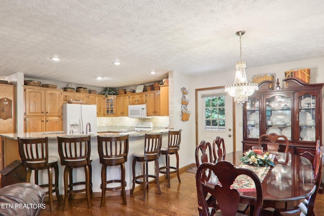 dining room with a textured ceiling, a notable chandelier, and dark hardwood / wood-style floors