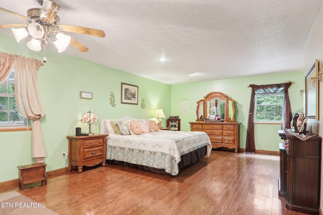 bedroom featuring ceiling fan, wood-type flooring, and a textured ceiling