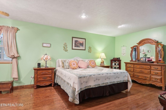 bedroom with a textured ceiling and dark hardwood / wood-style flooring