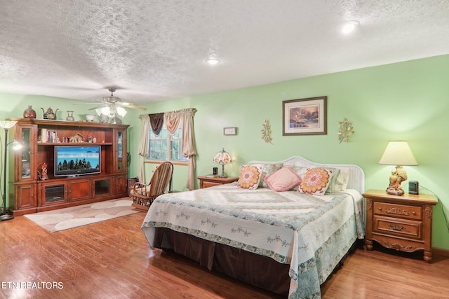 bedroom featuring hardwood / wood-style floors, ceiling fan, and a textured ceiling