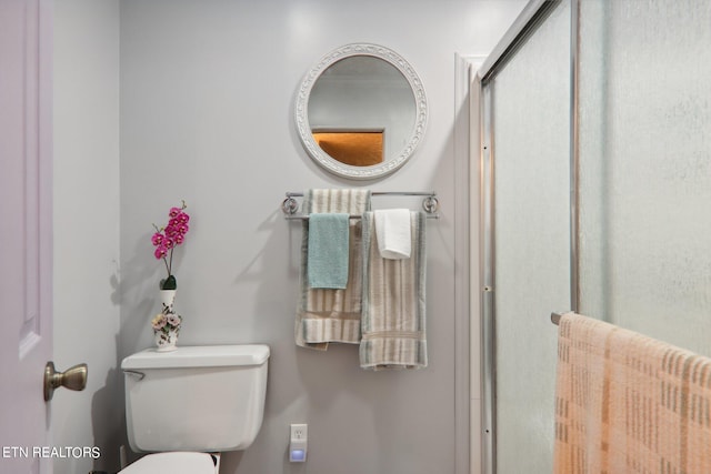 bathroom with a shower with shower door and toilet