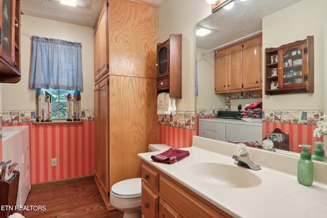 bathroom featuring a textured ceiling, vanity, independent washer and dryer, wood-type flooring, and toilet