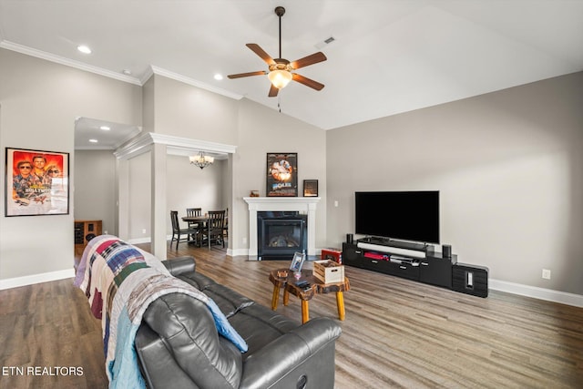 living room with vaulted ceiling, ornamental molding, ceiling fan with notable chandelier, and hardwood / wood-style flooring