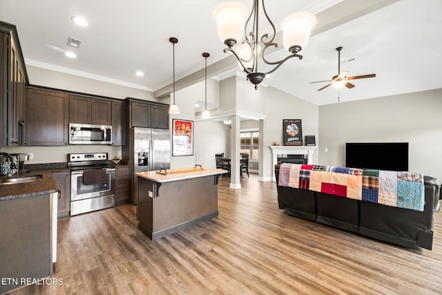 kitchen with a kitchen island, ceiling fan with notable chandelier, wood-type flooring, hanging light fixtures, and stainless steel appliances