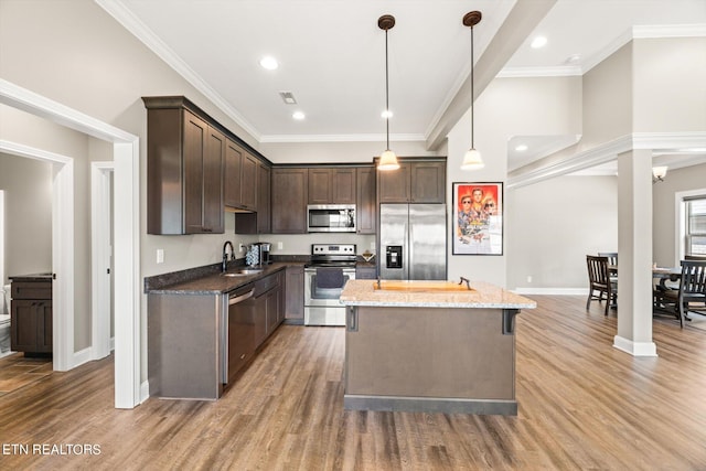 kitchen featuring wood-type flooring, a kitchen island, stainless steel appliances, and stone countertops