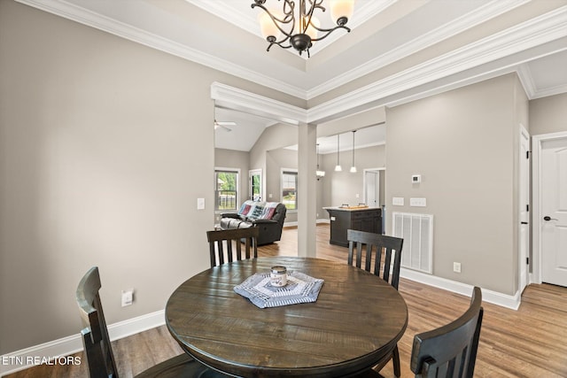 dining space featuring ceiling fan with notable chandelier, vaulted ceiling, ornamental molding, and hardwood / wood-style flooring