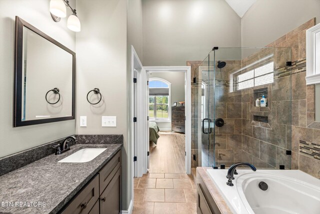 bathroom with tile patterned flooring, vanity, separate shower and tub, and vaulted ceiling