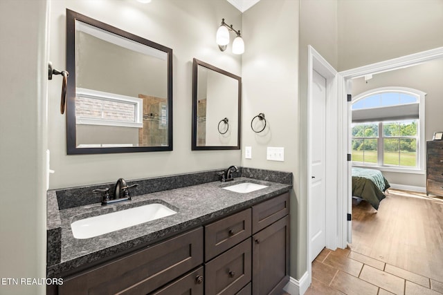 bathroom featuring double vanity, ensuite bath, baseboards, and a sink