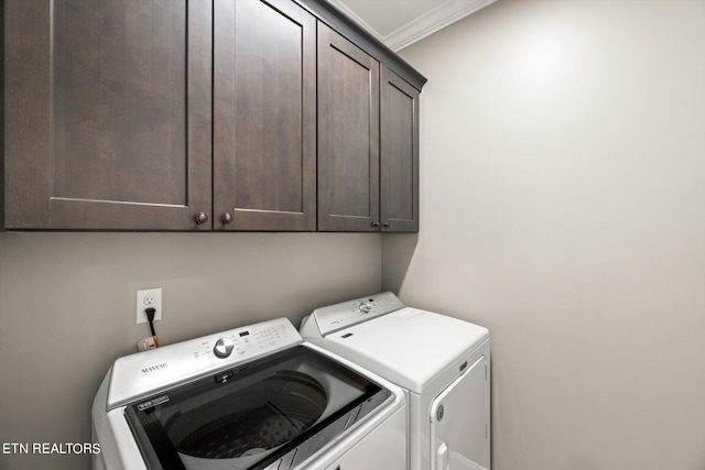 laundry area with ornamental molding, washing machine and clothes dryer, and cabinet space