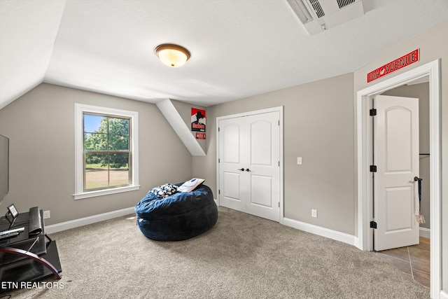 interior space featuring lofted ceiling, light carpet, and a textured ceiling