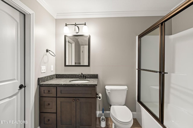 bathroom with baseboards, ornamental molding, toilet, vanity, and shower / bath combination with glass door